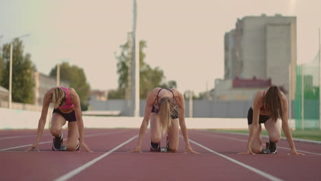 Three-female-track-and-water-athletes-start-the-race-at-the-stadium-in-running-pads-at-a-sprint-distance.-Women-track-and-track-and-file-runners-running-in-the-stadium